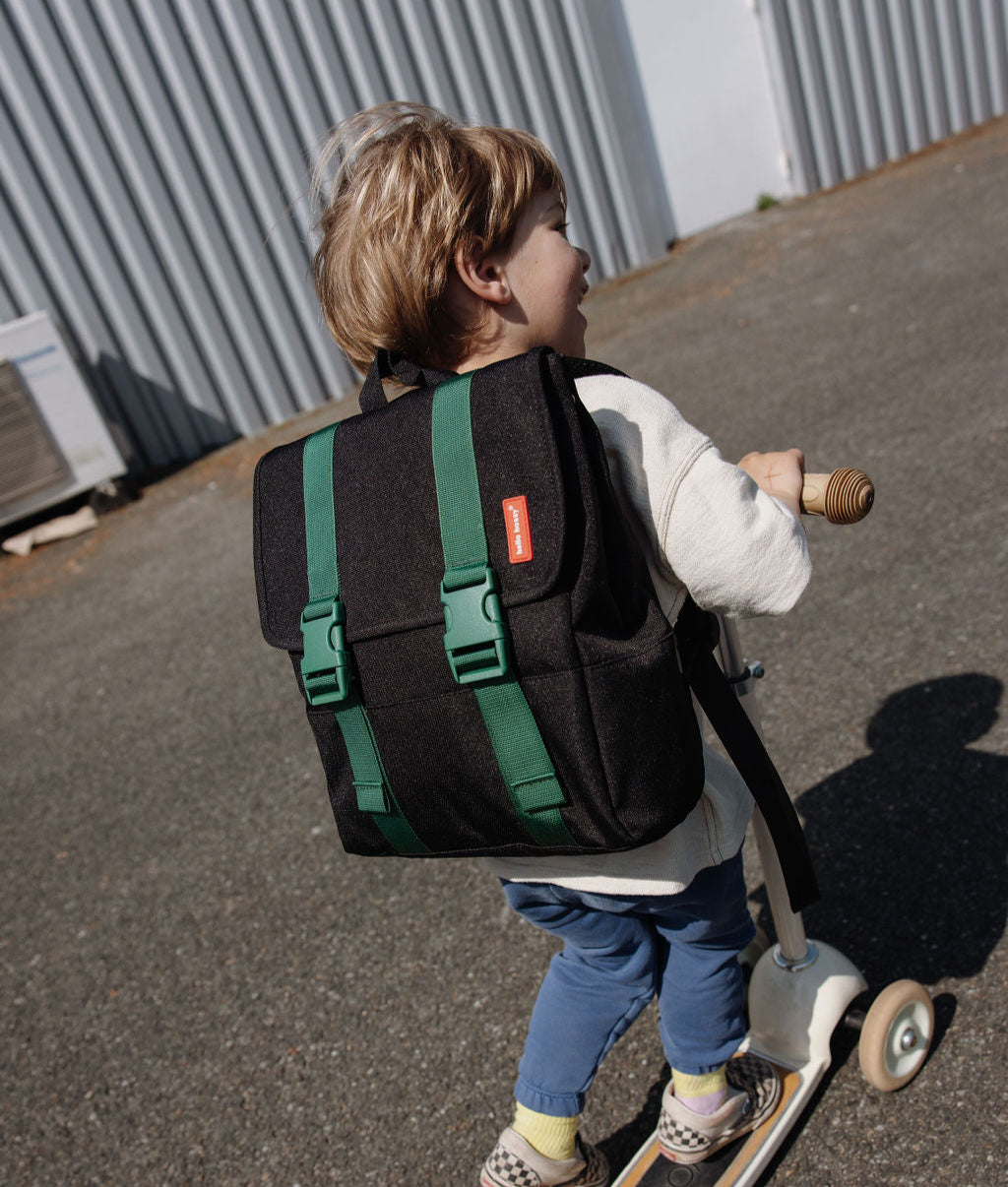 Mochila infantil preta com faixas verdes e fivelas à frente Hello Hossy