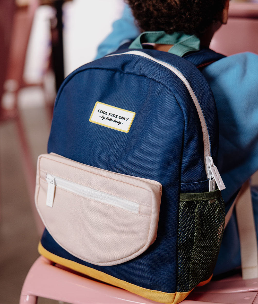 Mochila infantil azul, bolso bege, rede verde, base amarela, patch com texto Hello Hossy