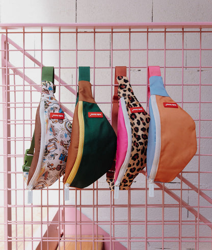 Bolsa de cintura infantil rosa com estampado leopard, fecho éclair branco e alça laranja Hello Hossy