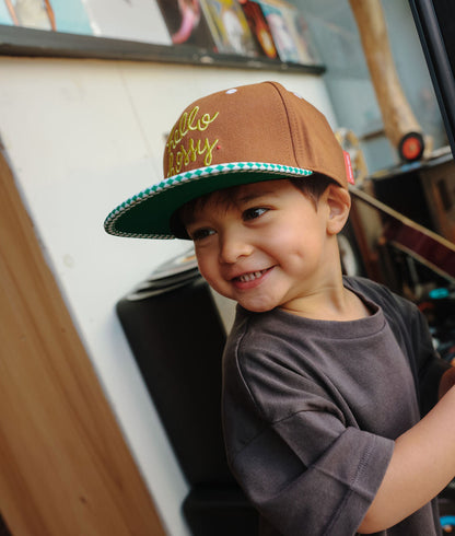 Boné infantil castanho, pala reta, padrões verdes, bordado Hello Hossy