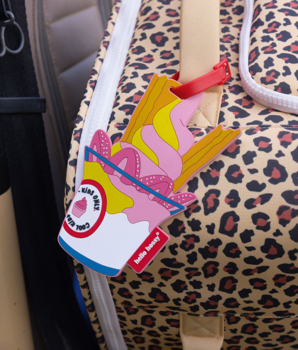 Etiqueta de mala de viagem infantil rosa com padrão de gelado numa mala de viagem estampada leopard, Hello Hossy