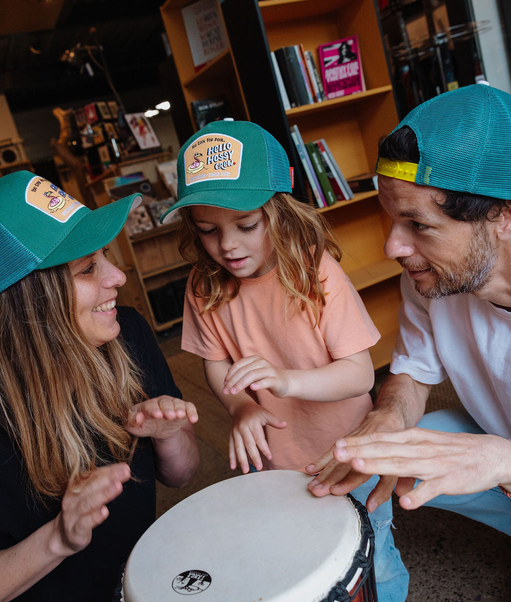 Duo de família com bonés verdes e patch Hello Hossy usados por mãe, criança e pai Hello Hossy