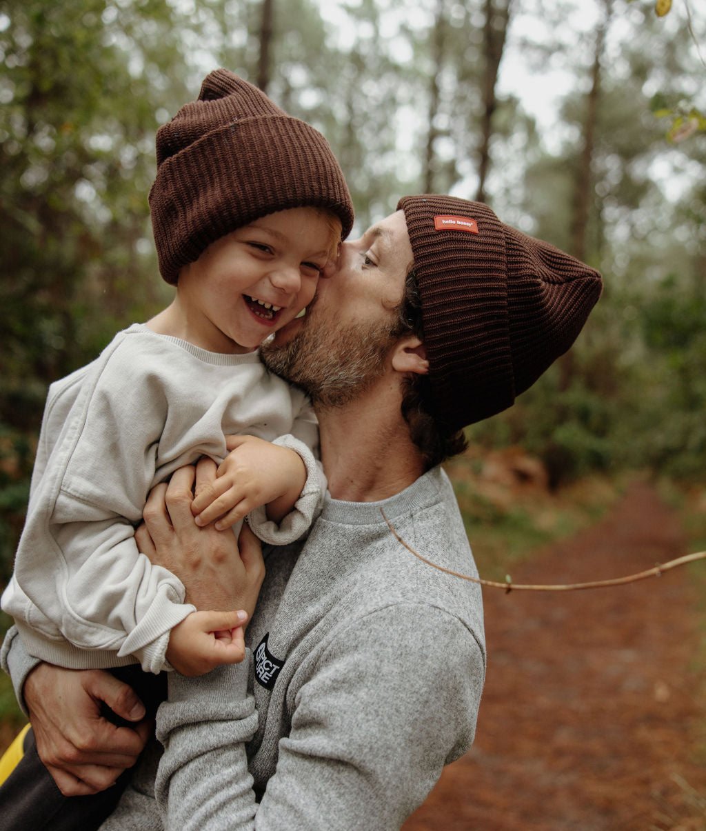 Duo pai-criança com gorros castanhos a combinar e etiqueta cosida Hello Hossy