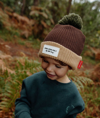 Gorro infantil castanho com rebordo bege, pompom verde e etiqueta cosida Hello Hossy
