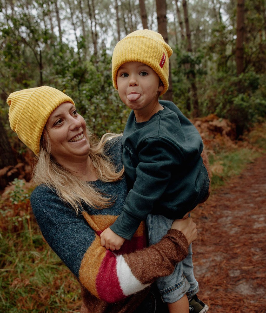 Duo mãe e criança com gorros amarelos de dobra e etiqueta vermelha Hello Hossy