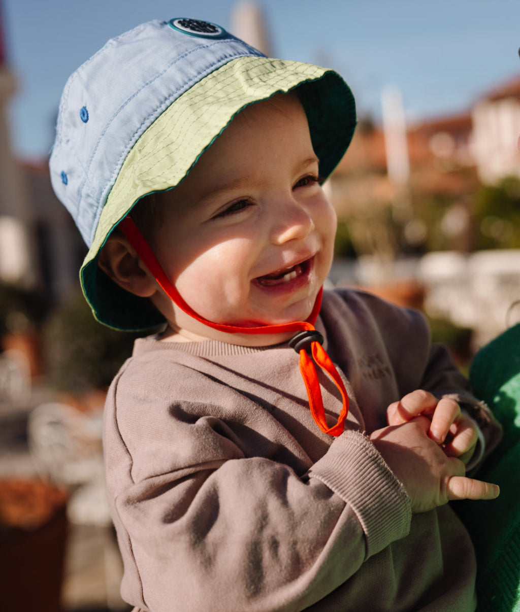 Chapéu bucket infantil bicolor azul e verde, cordão vermelho, patch redondo Hello Hossy
