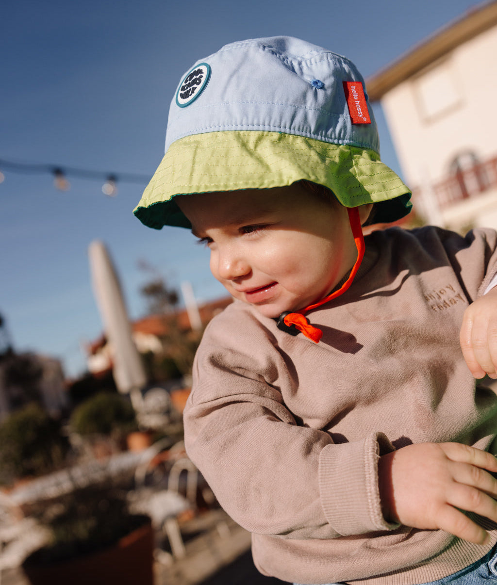 Chapéu bucket infantil bicolor azul e verde, cordão vermelho, patch redondo Hello Hossy