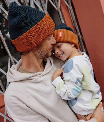 Gorro de malha bicolor usado por um pai e o filho que segura nos braços - vista de perfil - Hello Hossy