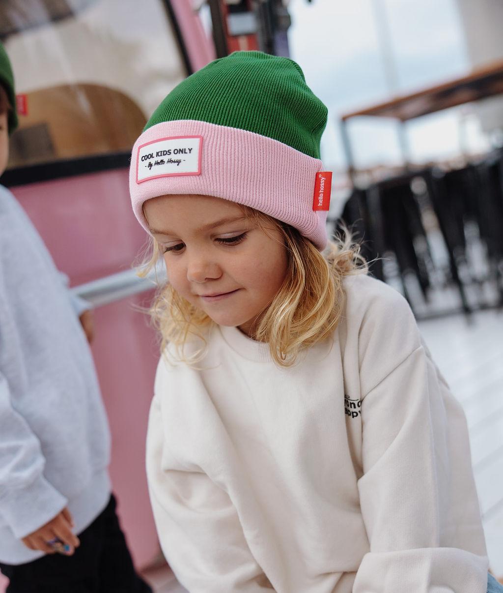 Gorro infantil verde com rebordo rosa e etiqueta com texto Hello Hossy