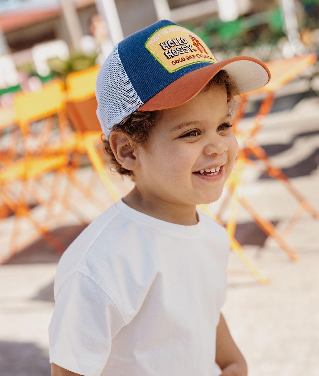 Criança com boné azul e laranja, rede branca, patch Hello Hossy