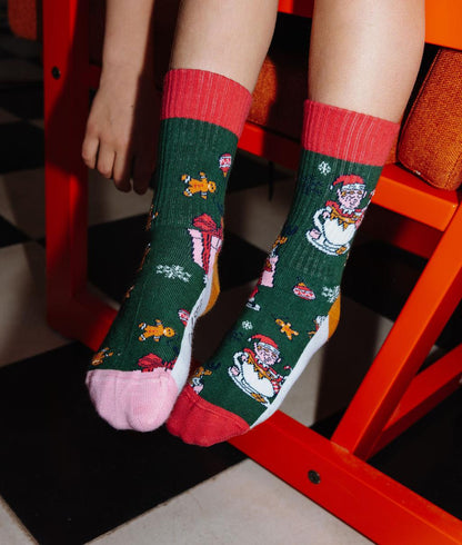 Par de meias verdes com padrão de natal, calcanhares e pontas coloridos, usadas por uma criança – foto lifestyle – Hello Hossy
