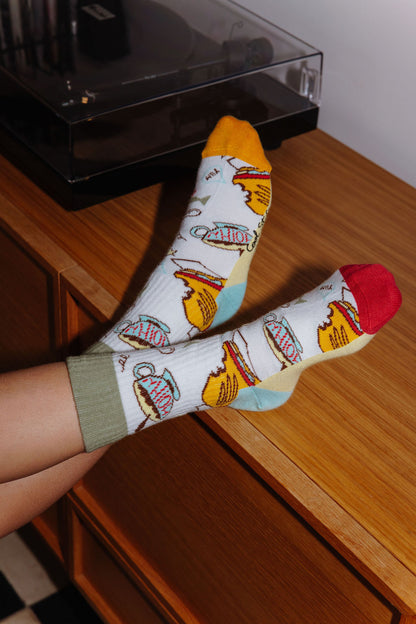 Criança a usar um par de meias estampadas com sanduíche e batatas fritas – vista de cima – Hello Hossy