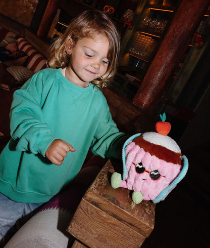 Menina de pé a segurar a Peluche original Cherry Cake pousada numa rampa - vista frontal - Hello Hossy