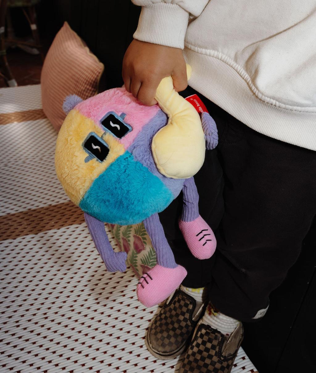 Peluche suave Disco Pop com nota musical em relevo, segurado por uma criança – vista de cima – Hello Hossy