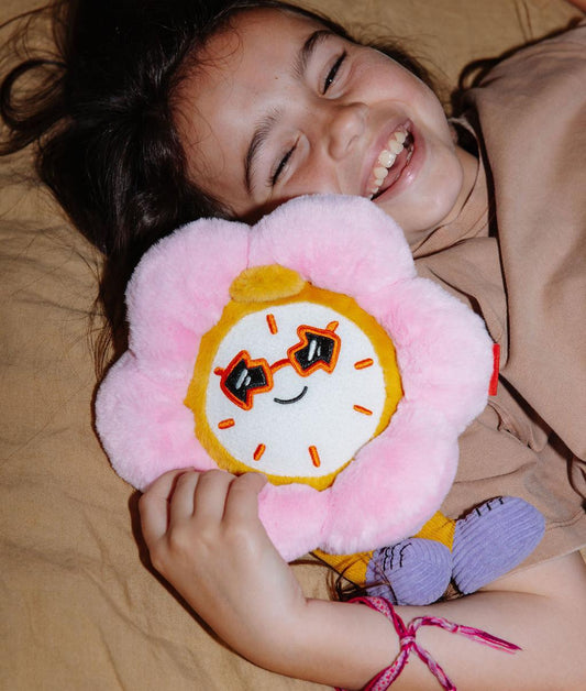 Menina deitada a segurar a Peluche em forma de relógio-flor Tic Tac Bloom junto a si - foto lifestyle - Hello Hossy