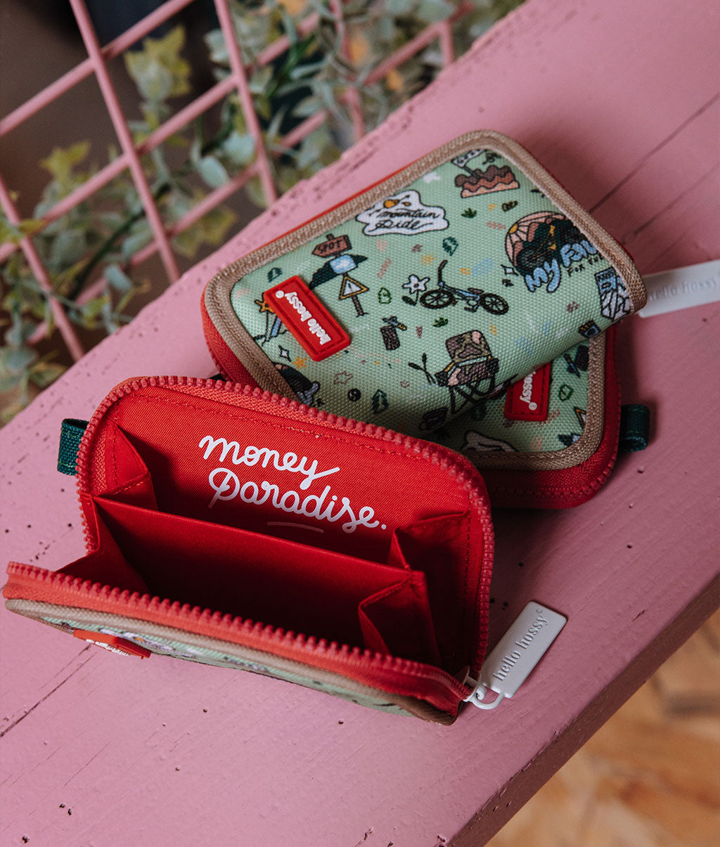 Porta-moedas infantil verde com padrão de viagem e bicicleta, rebordo bege e interior vermelho Hello Hossy