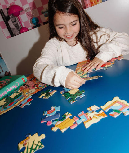 Menina a montar o Puzzle ilustrado "Cherry Safari" numa mesa – foto lifestyle – Hello Hossy