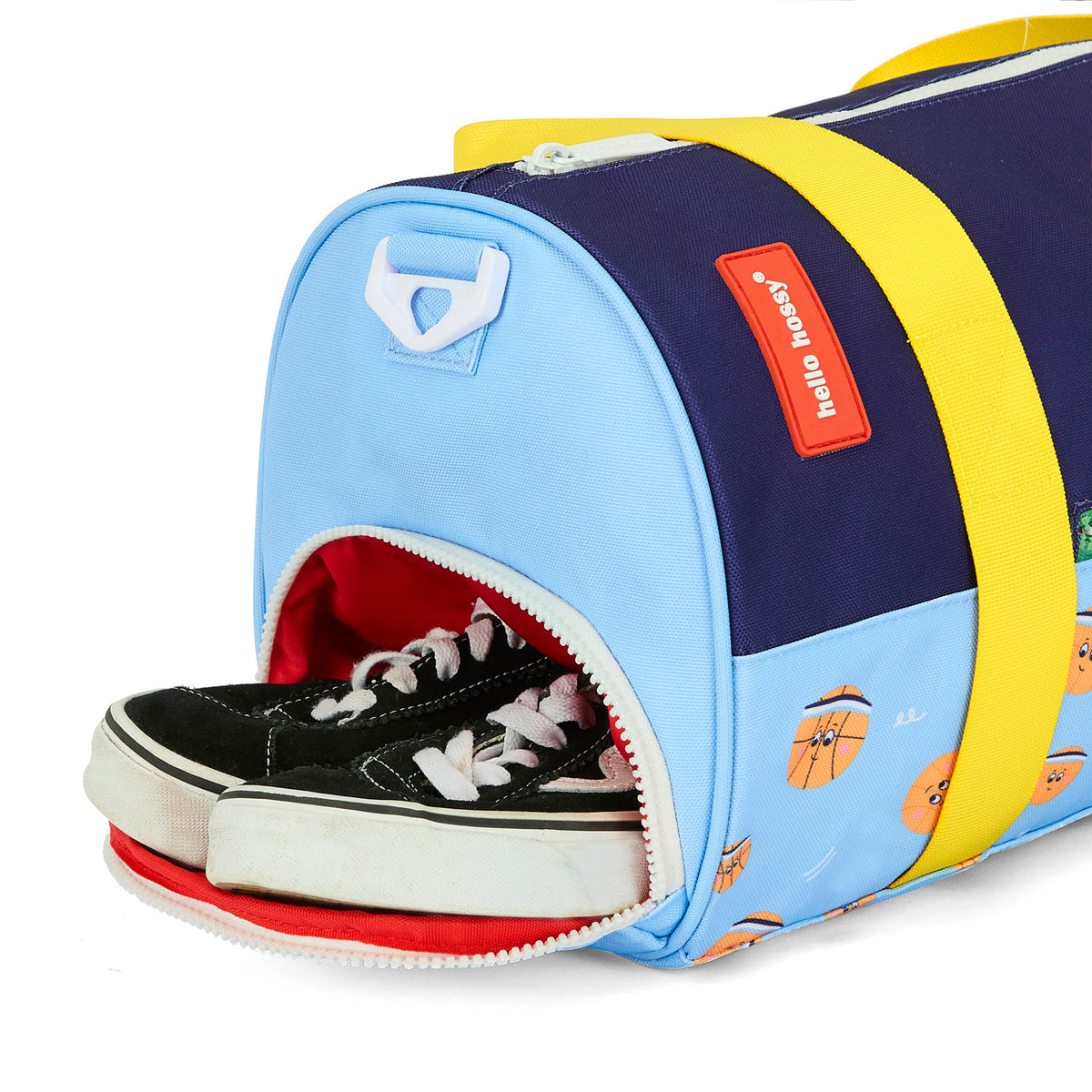 Saco de desporto infantil azul, verde e laranja com padrões de desporto, detalhe do fecho Hello Hossy