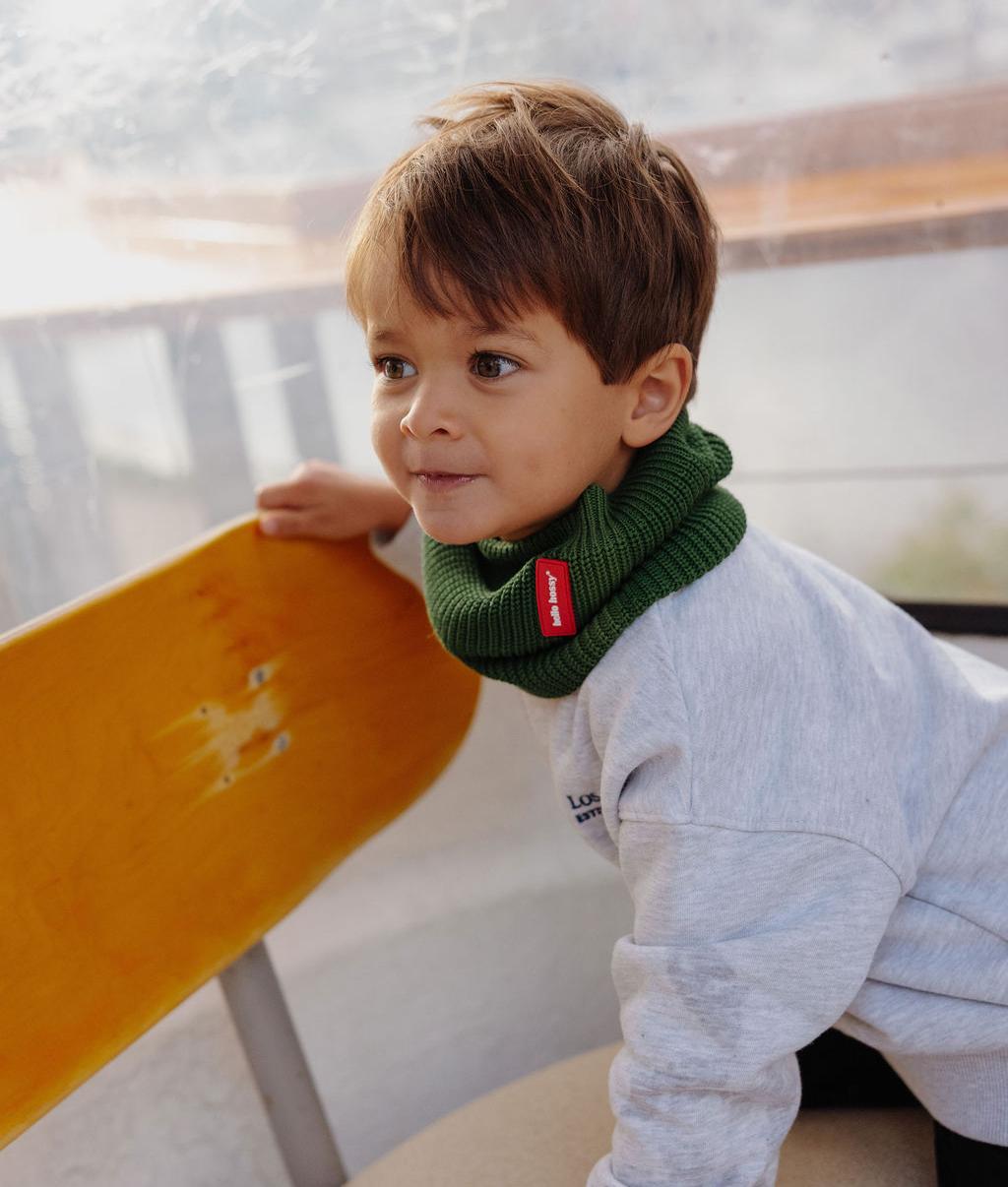 Criança a usar Snood verde em malha canelada, etiqueta vermelha Hello Hossy