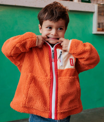 Criança com casaco polar laranja e bege, bolso com fecho Hello Hossy